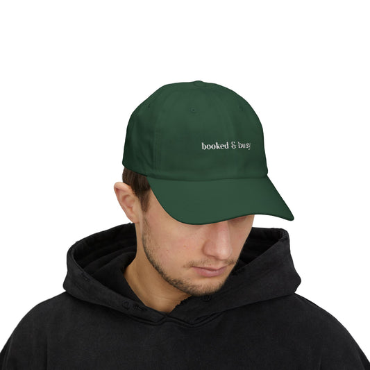 Person wearing a green cap with 'booked & busy' text on a white background