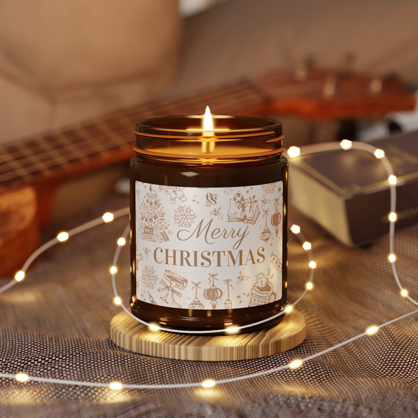 Candle in a jar with 'Merry Christmas' label on a wooden coaster, surrounded by string lights and a guitar in the background.