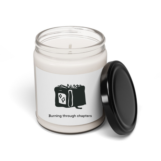 A soy candle in a clear glass jar with a black lid, featuring a custom label with book-themed artwork and text that reads 'Burning through chapters'. The jar is labeled 'Make It Yours'.