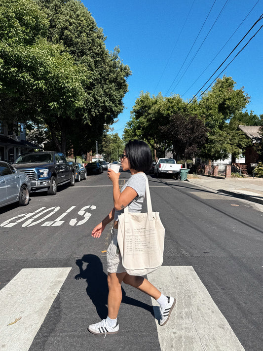 Person walking on a street holding a coffee cup and a bag