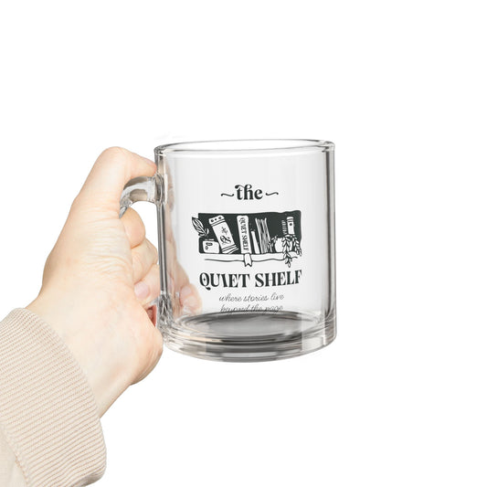 Clear mug with 'The Quiet Shelf' design held by a hand on a white background