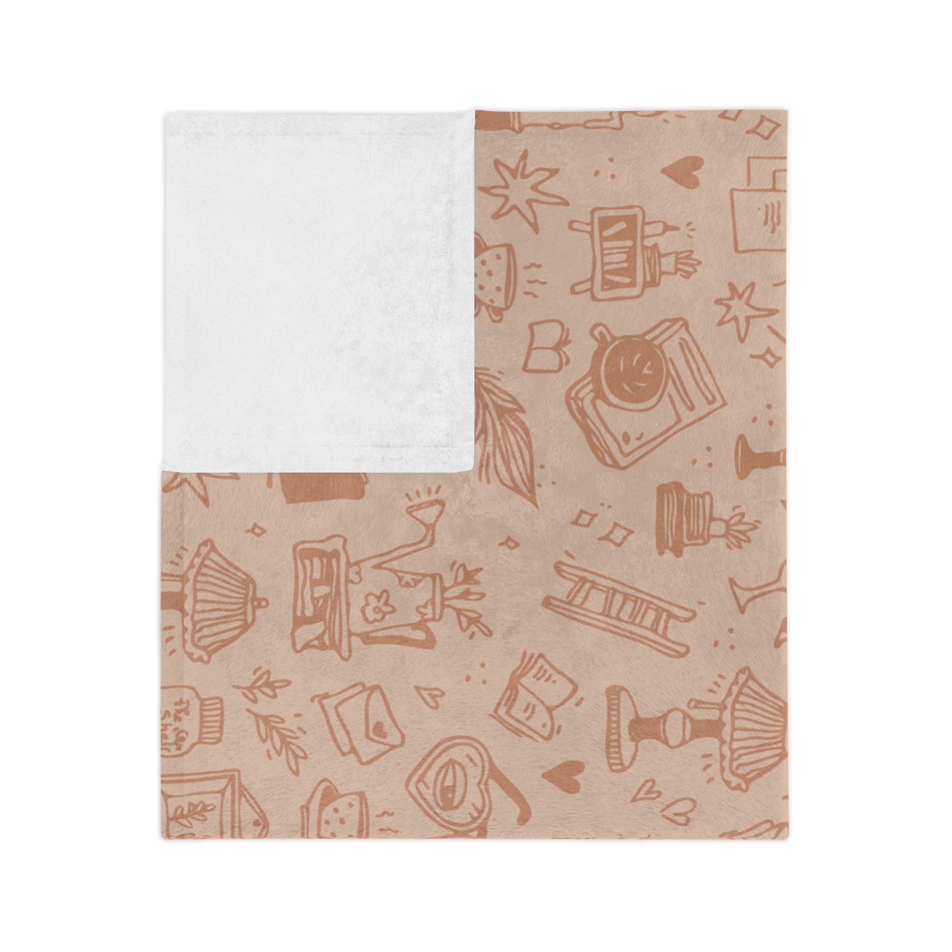 A blush pink blanket with a subtle book-themed pattern, including illustrations of pages, books, and reading accessories, laid out flat.