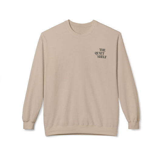 A beige crewneck sweatshirt with 'THE QUIET SHELF' written in a small, bold font on the upper left front side.