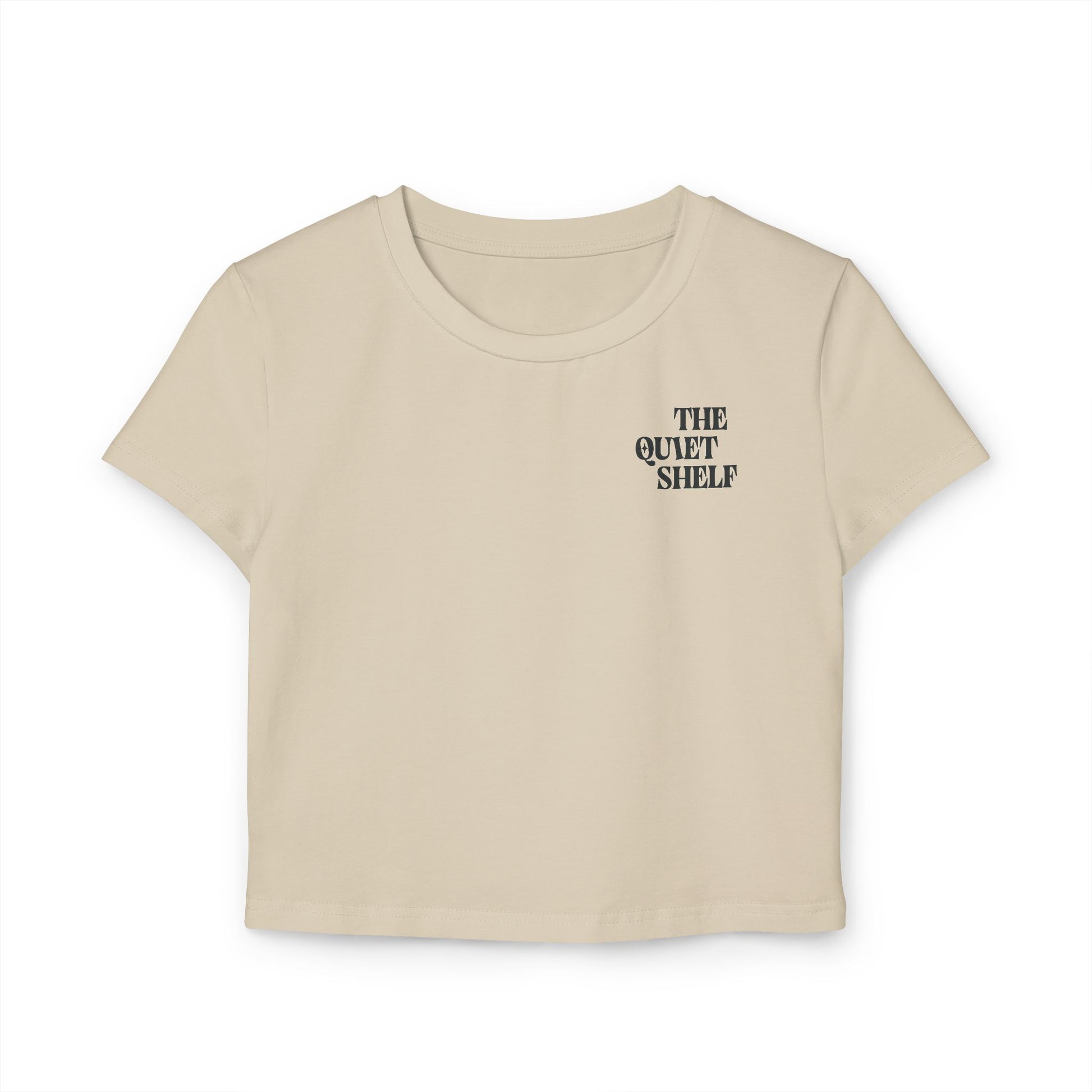 A beige cropped tee with 'THE QUIET SHELF' logo printed on the upper left chest area.