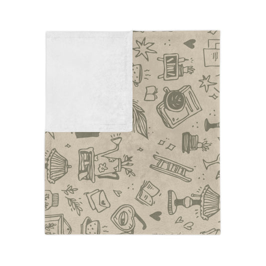 A blanket with a custom pattern featuring bookish elements, such as books, glasses, and envelopes, on a beige background.