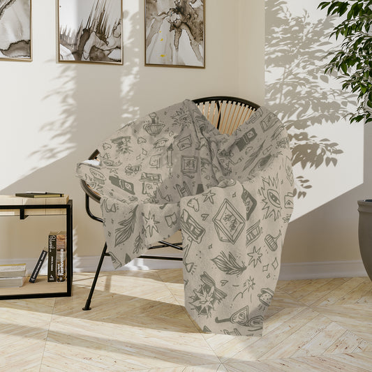 Patterned blanket draped over a chair in a room with light wood flooring and white walls.