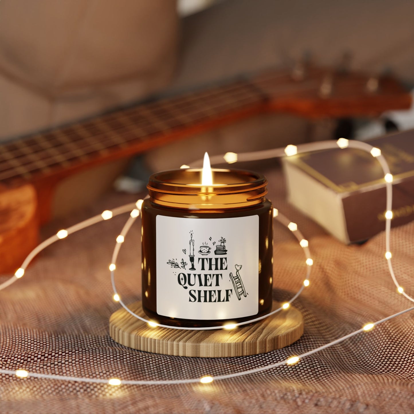 A soy candle in an amber glass jar with a black lid, featuring a minimalist label with bookish elements and the text 'THE QUIET SHELF'