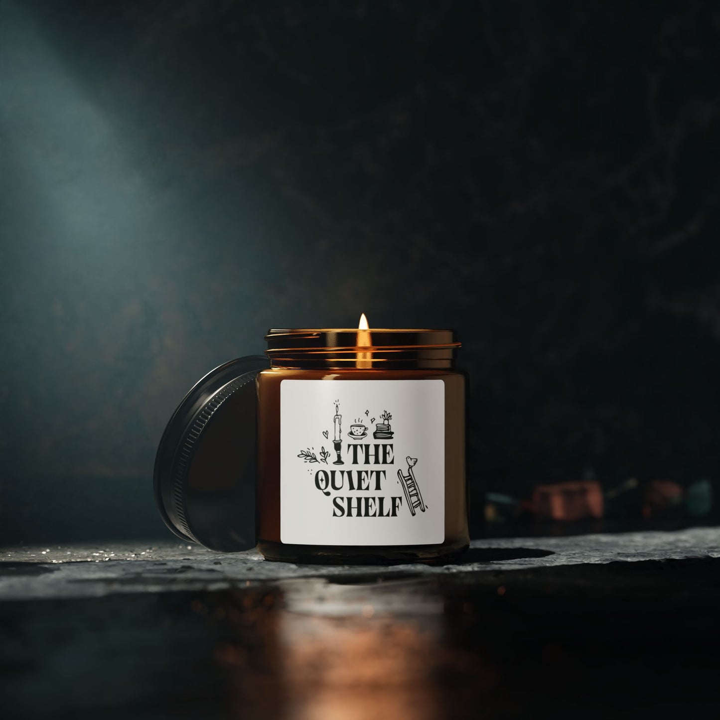 A soy candle in an amber glass jar with a black lid, featuring a minimalist label with bookish elements and the text 'THE QUIET SHELF'.