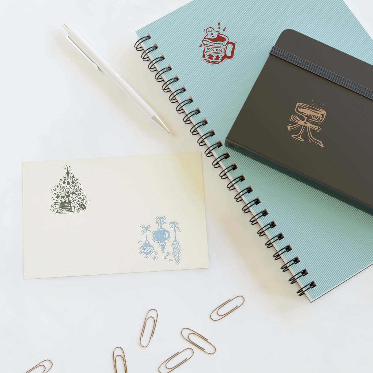 Notebooks with decorative covers and paper clips on a white surface
