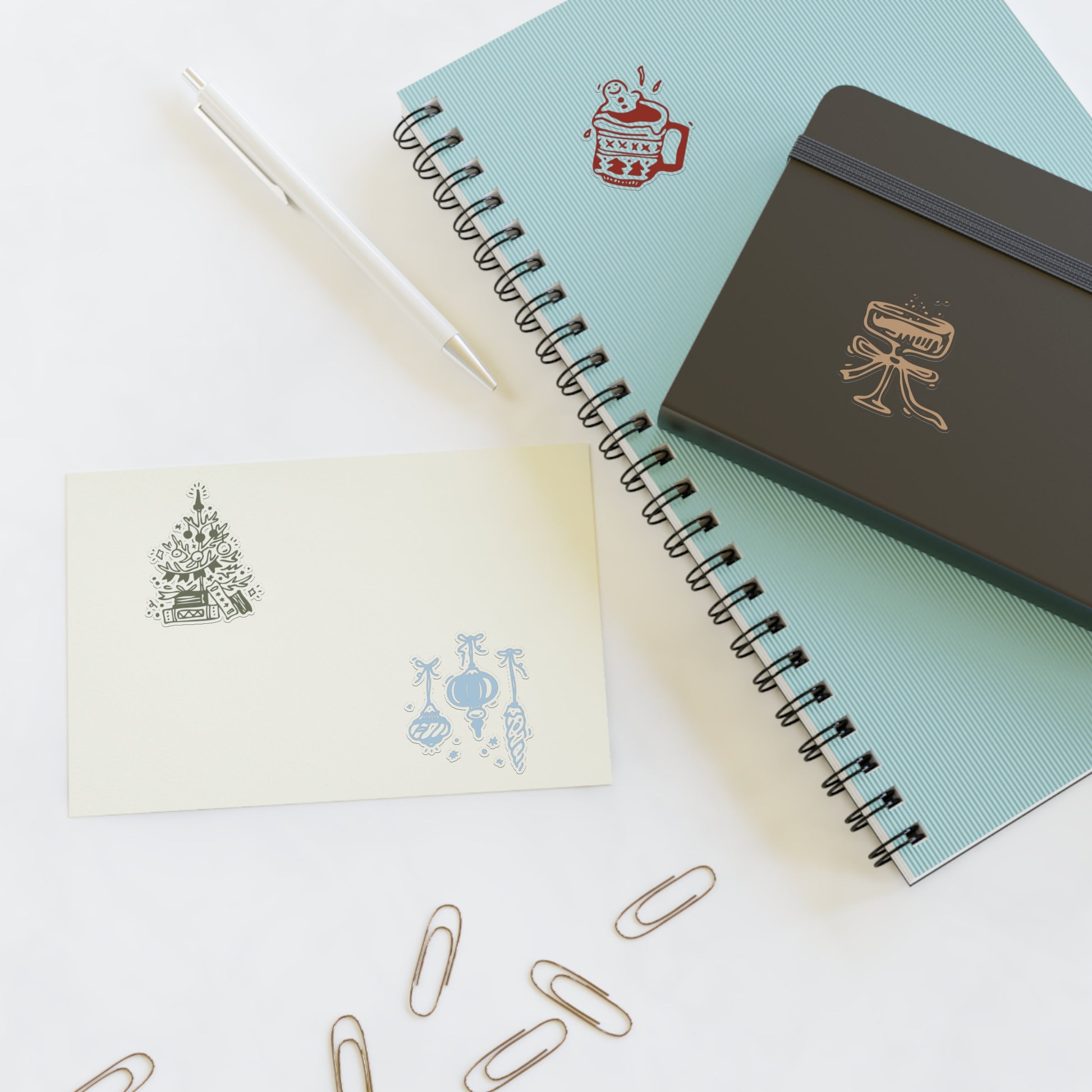 Notebooks with decorative covers and paper clips on a white surface
