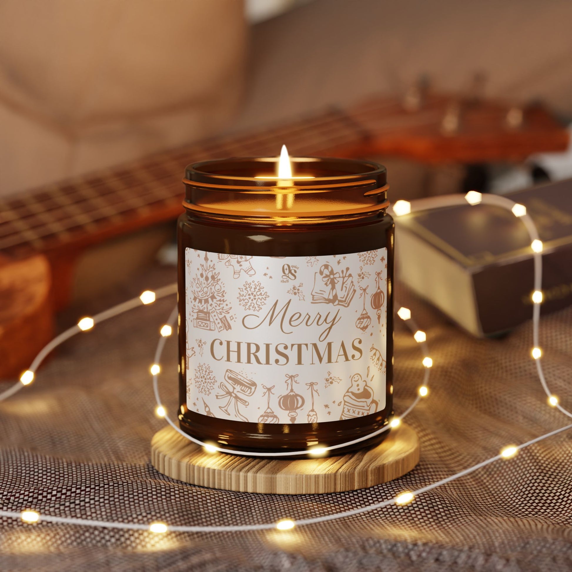 Candle in a jar with 'Merry Christmas' label on a wooden coaster, surrounded by string lights and a guitar in the background.