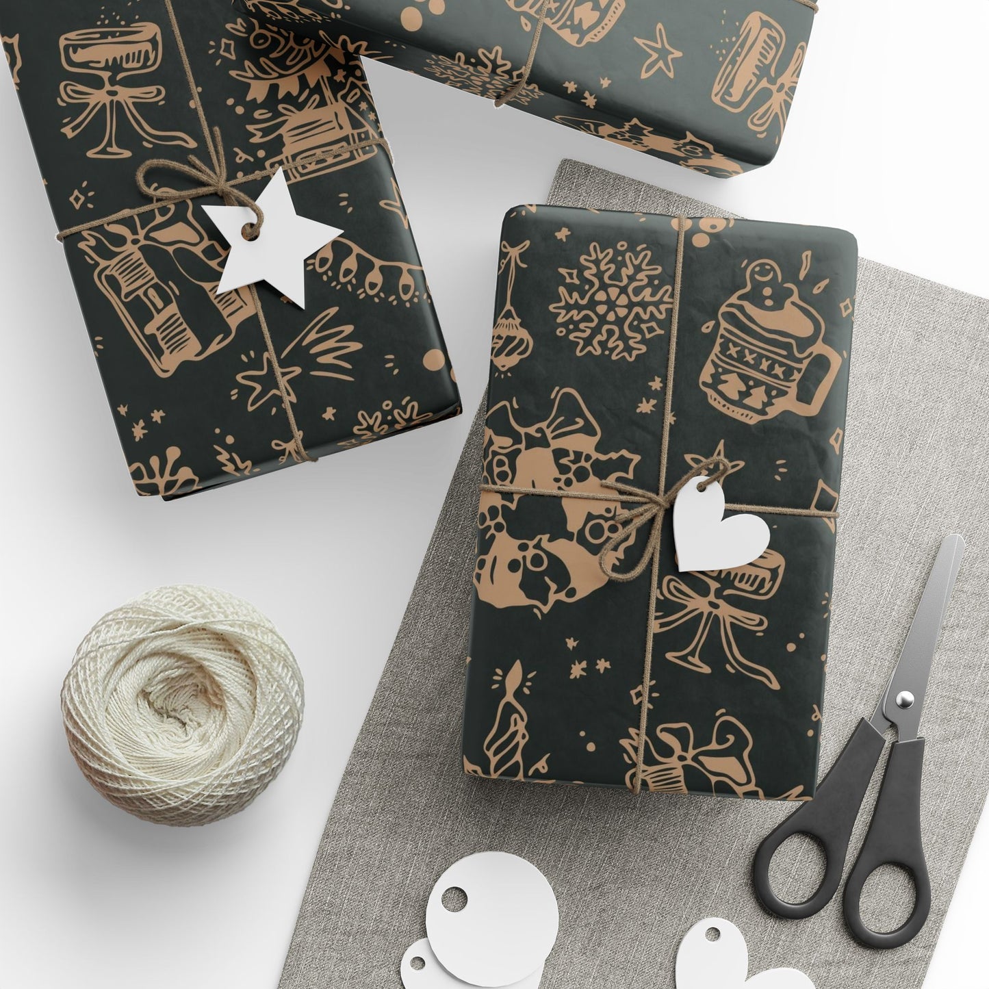 Dark green wrapping paper with gold patterns, scissors, and a ball of yarn on a white surface.