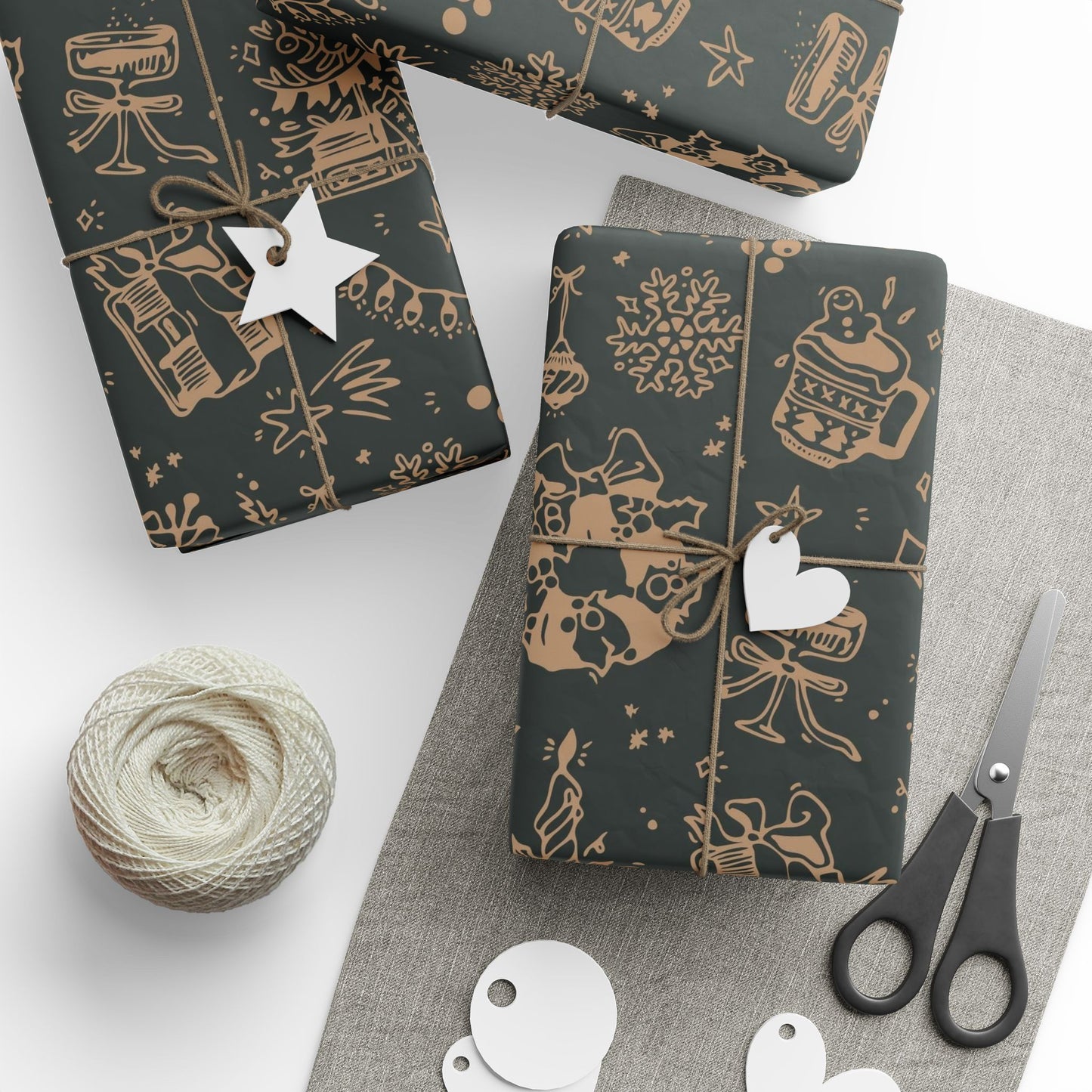 Dark gift wrap paper with gold patterns, scissors, and yarn on a white surface