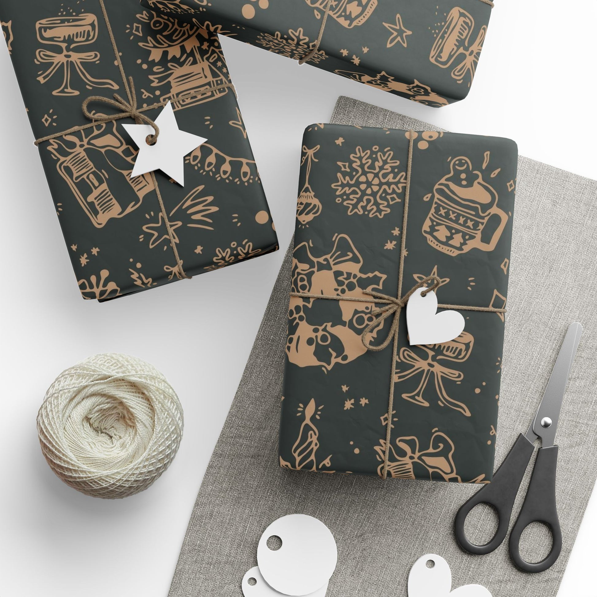 Dark gift wrap paper with gold patterns, scissors, and yarn on a white surface