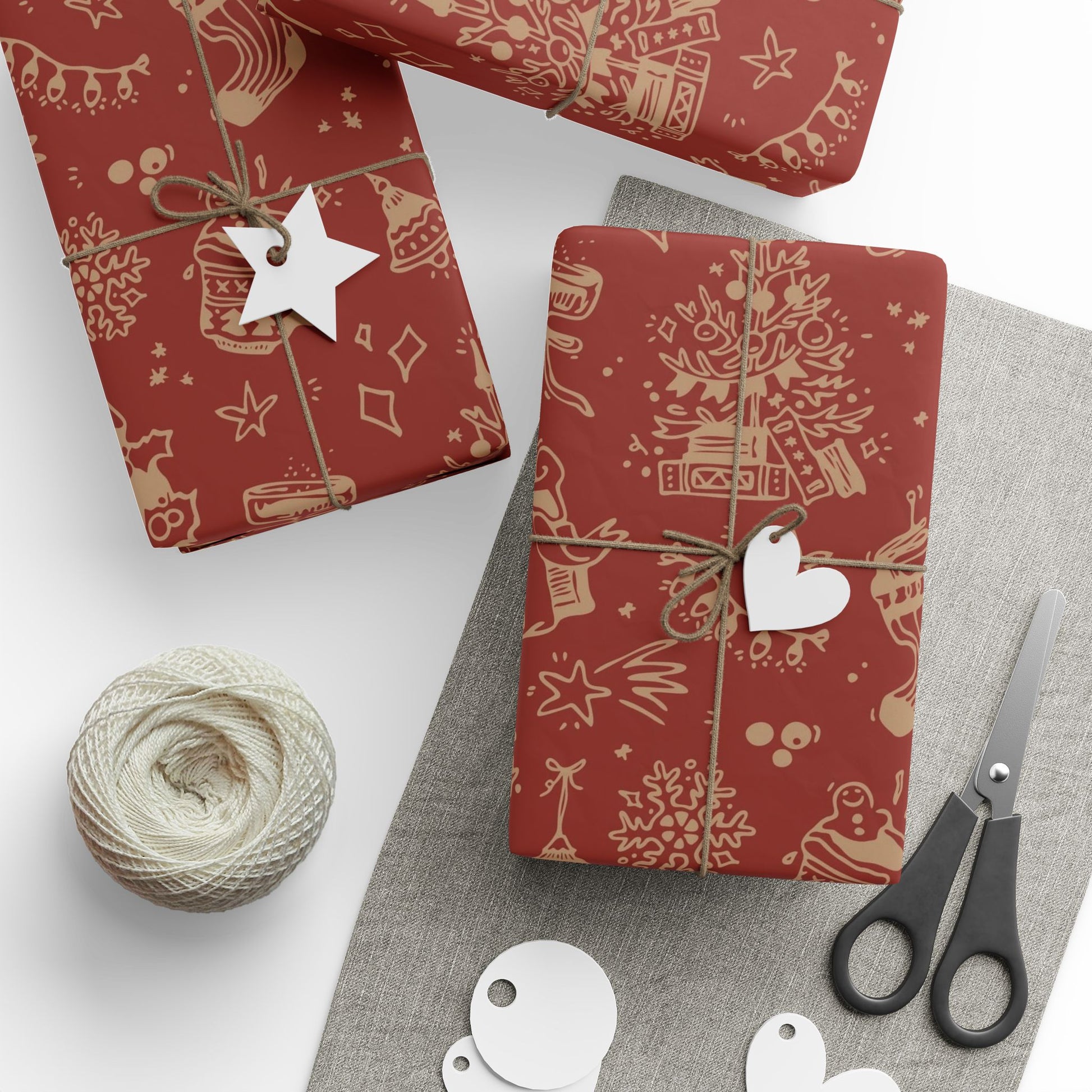 Red gift wrap with festive patterns, scissors, and a ball of twine on a white background