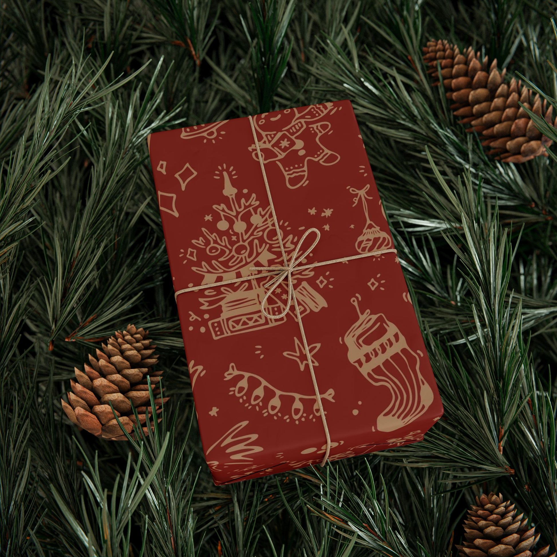 Red gift box with Christmas design on a bed of pine needles and pine cones