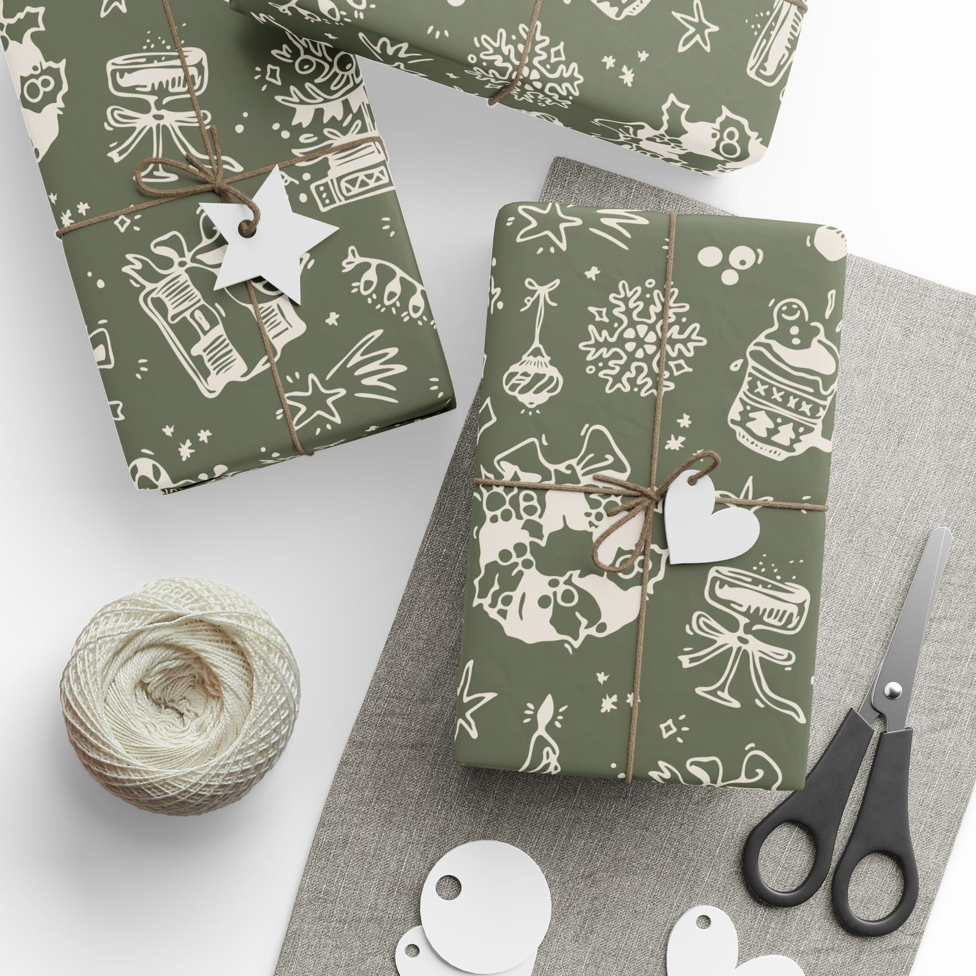 Gift boxes wrapped in green paper with white patterns, scissors, and yarn on a gray surface.