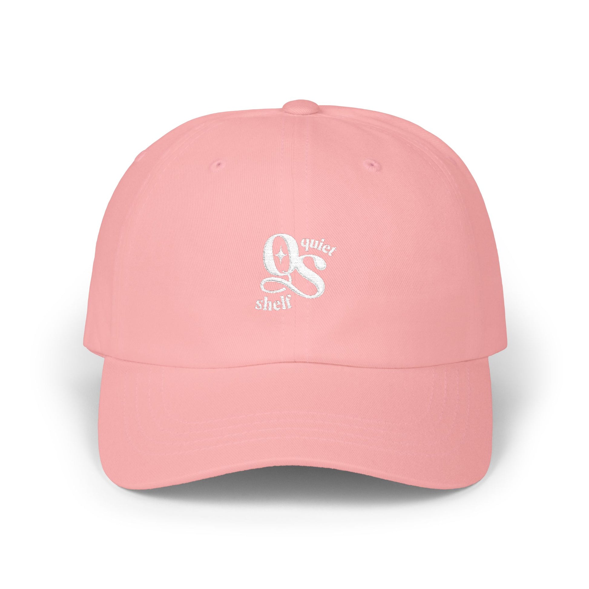 A pink dad hat with the Quiet Shelf's 'QS' logo embroidered in white on the front.