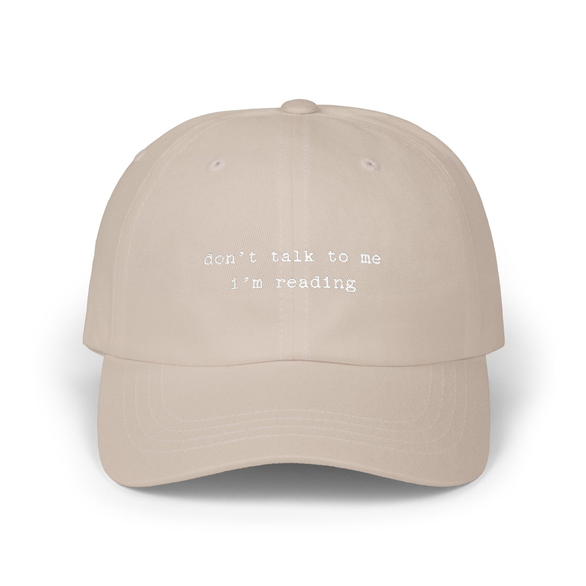 Beige cap with 'don't talk to me I'm reading' text on a white background