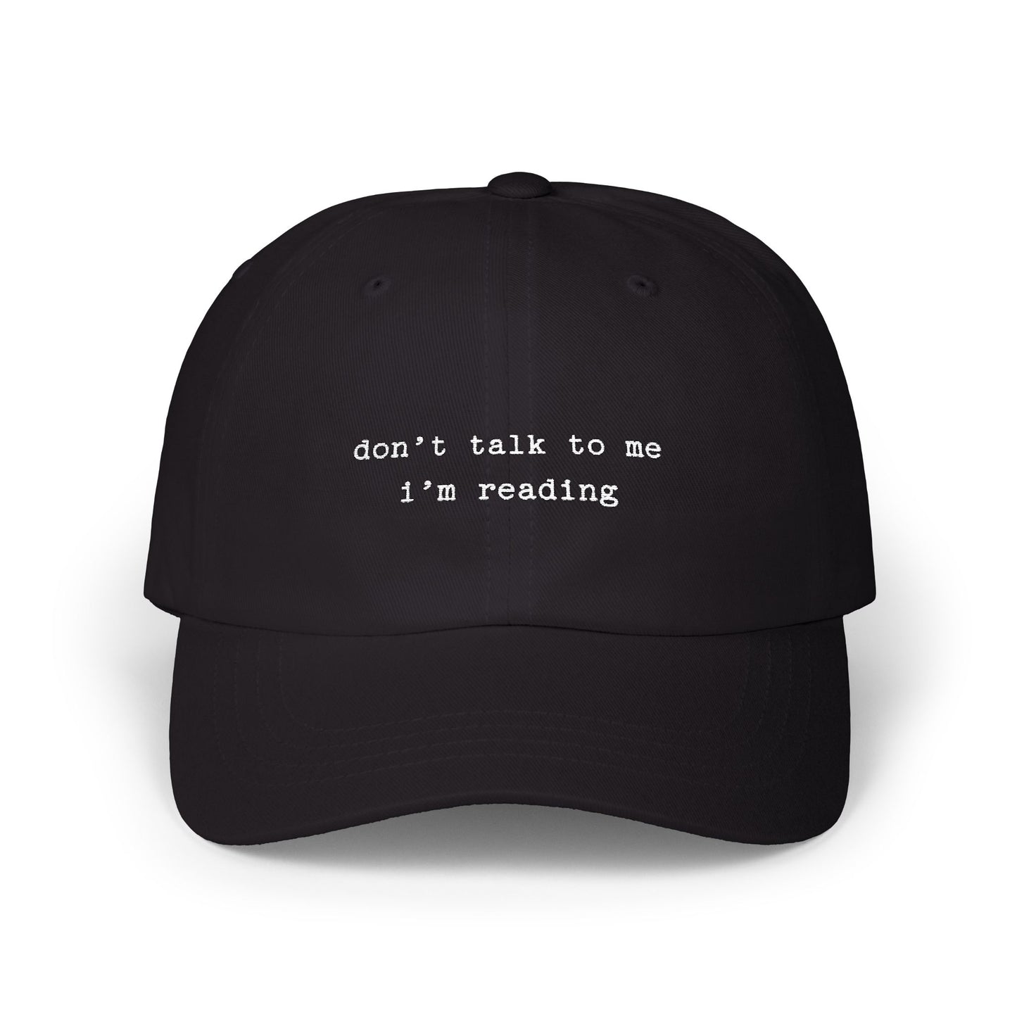 Black cap with 'don't talk to me I'm reading' text on a white background