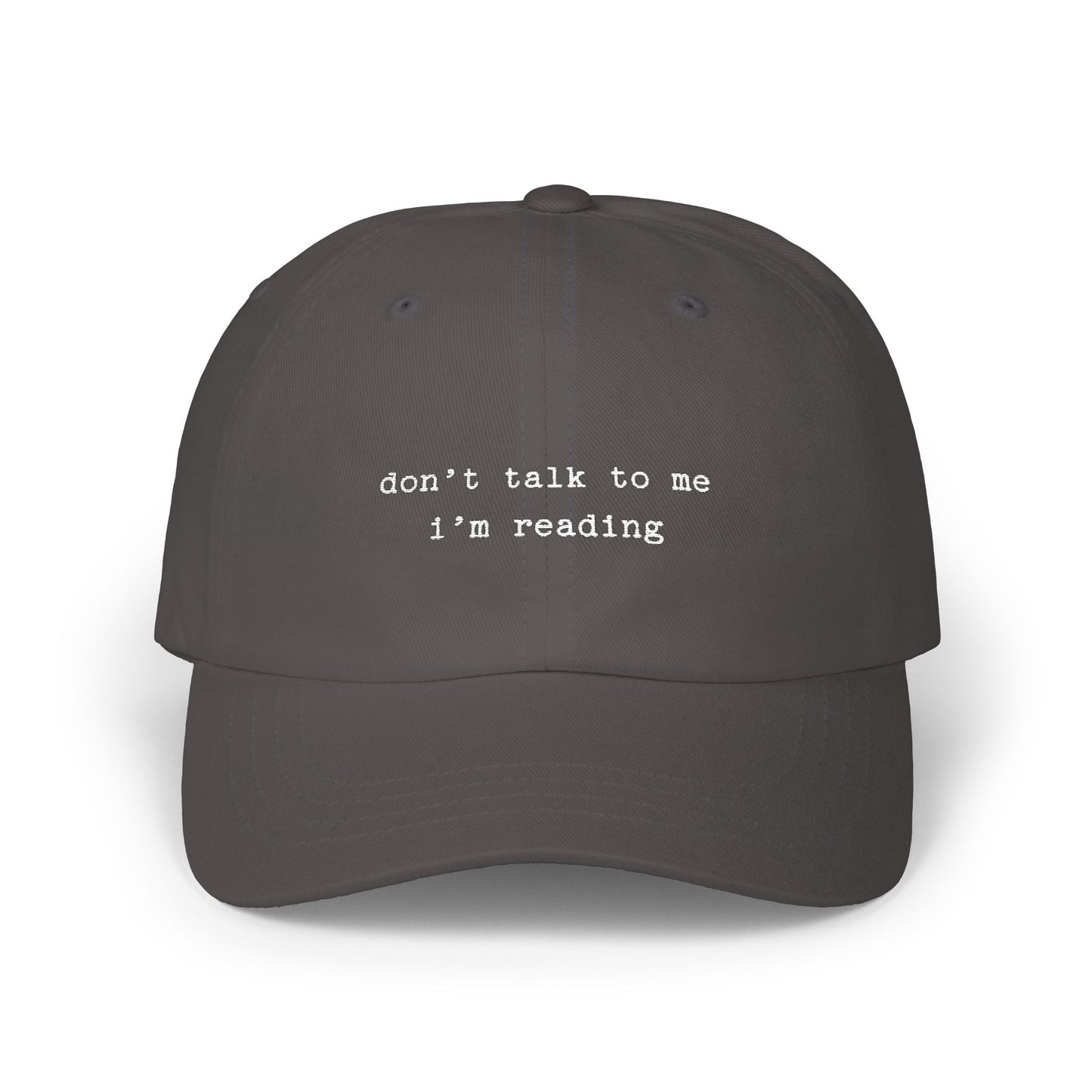 Dark gray cap with 'don't talk to me I'm reading' text on a white background