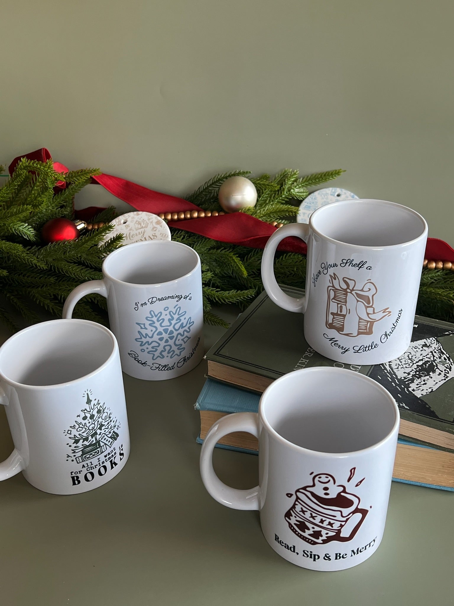 Four white mugs with various designs on a surface with a decorative background.