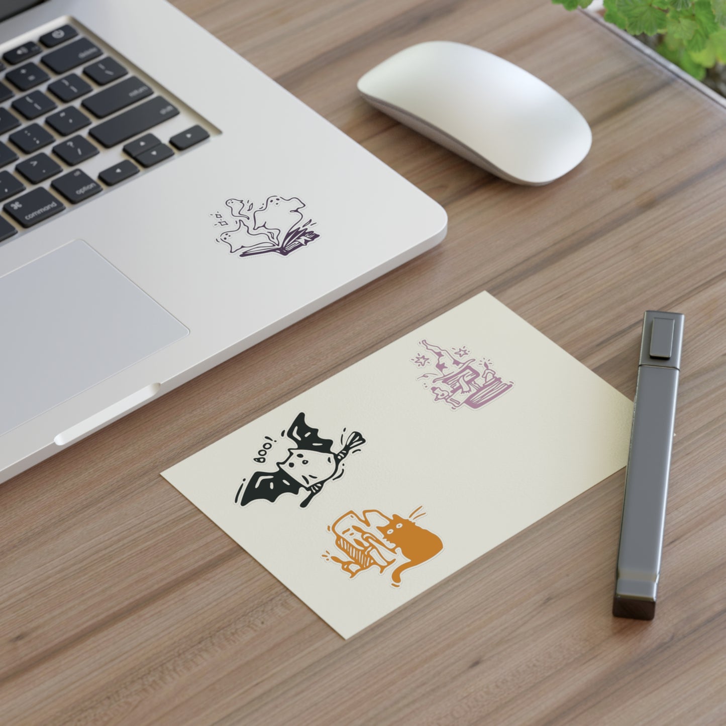 Laptop on a wooden desk with decorative stickers and a pen.