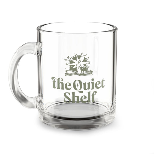 A clear glass mug with 'The Quiet Shelf' logo printed on the front.