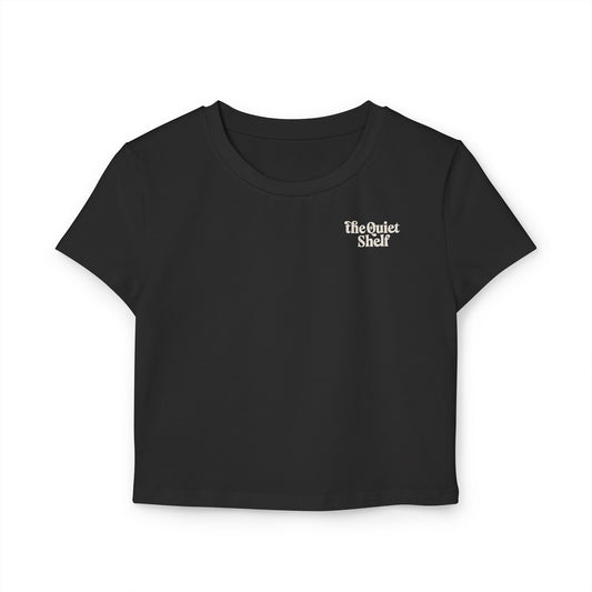 A black cropped tee with 'The Quiet Shelf' logo printed on the upper left front side, featuring a crew neck and short sleeves.