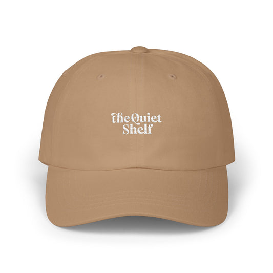 A beige dad hat with 'The Quiet Shelf' logo embroidered in the center.
