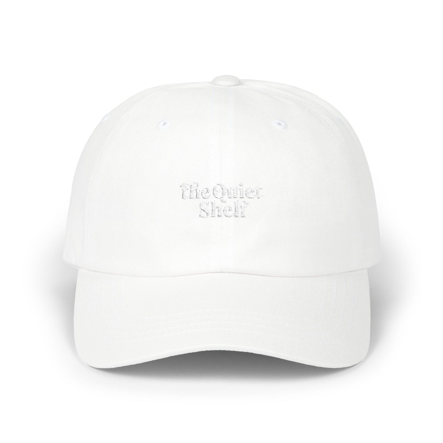 A white dad hat with 'The Quiet Shelf' logo embroidered in the center.