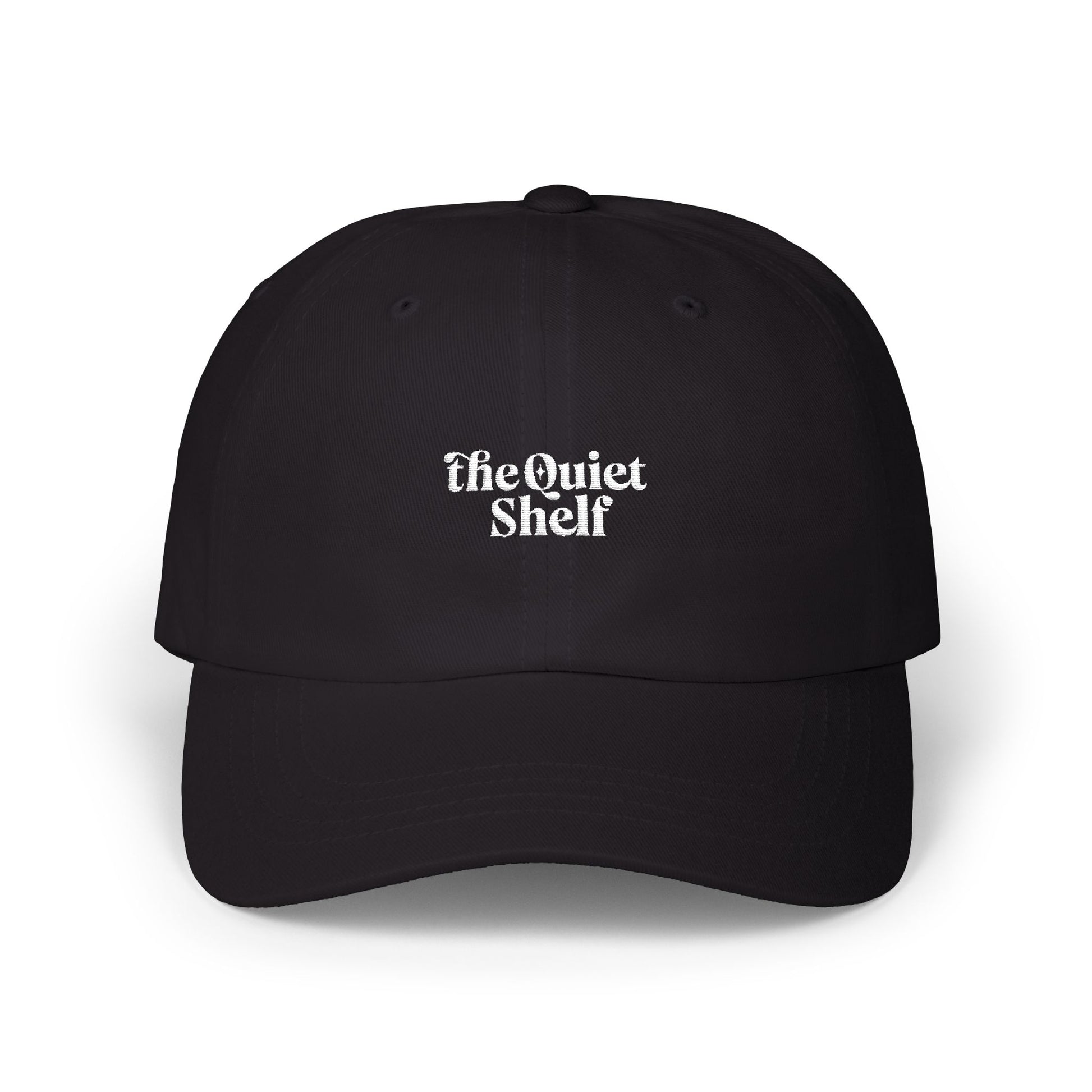 A black dad hat with 'The Quiet Shelf' logo embroidered in the center.