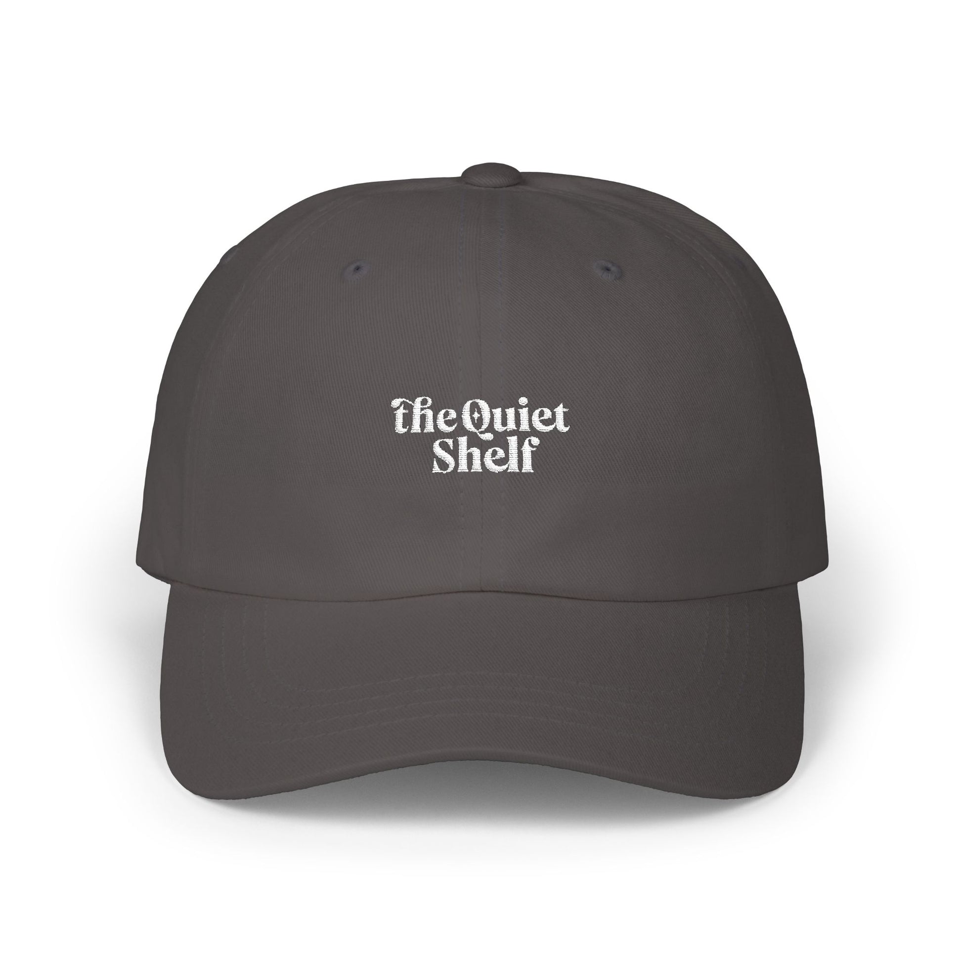 A dark dad hat with 'The Quiet Shelf' logo embroidered in the center.