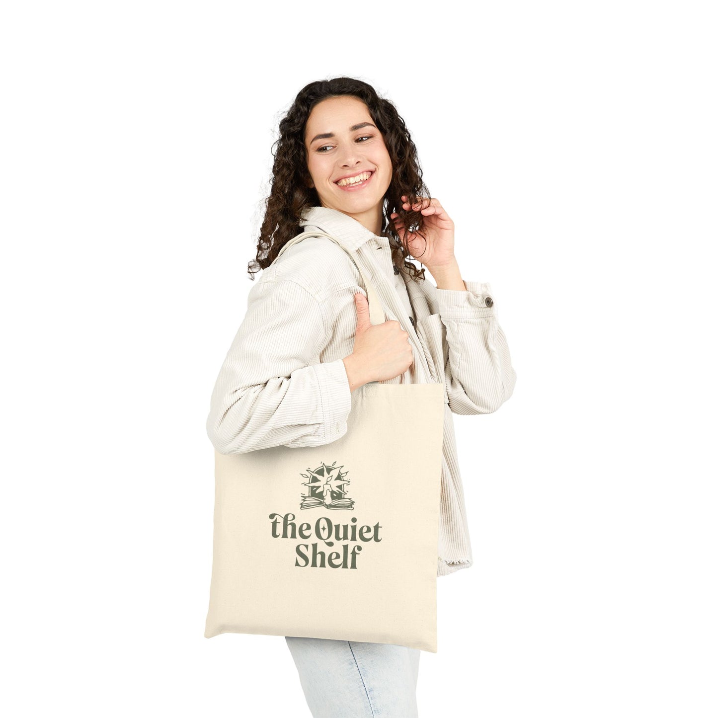 Woman carrying a beige tote bag with The Quiet Shelf logo on it