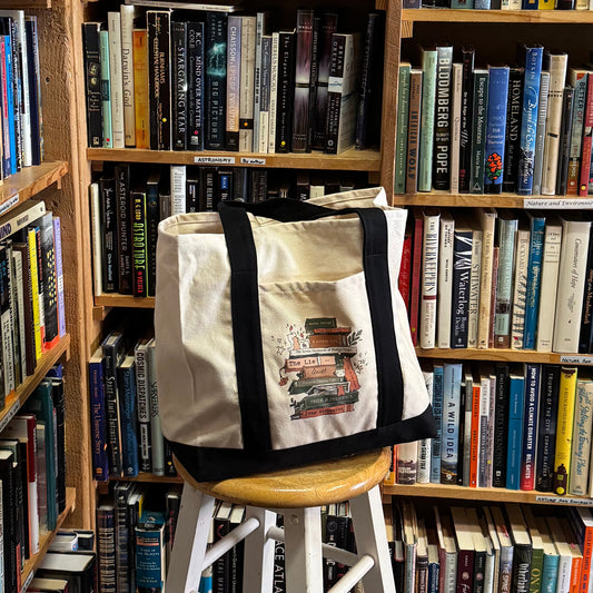 Tote bag with book design on a stool in front of bookshelves
