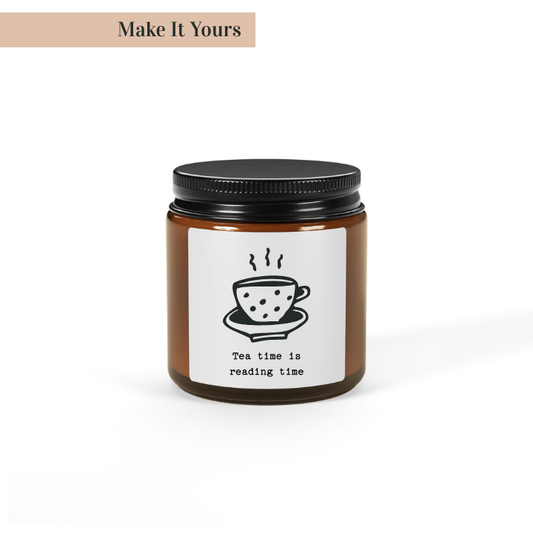 A soy wax candle in an amber glass jar with a black lid. The label has a white background with a coffee cup illustration and the text 'The time is reading time'.