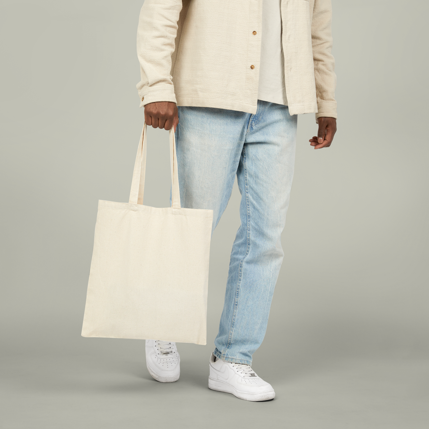 Man carrying a beige tote bag