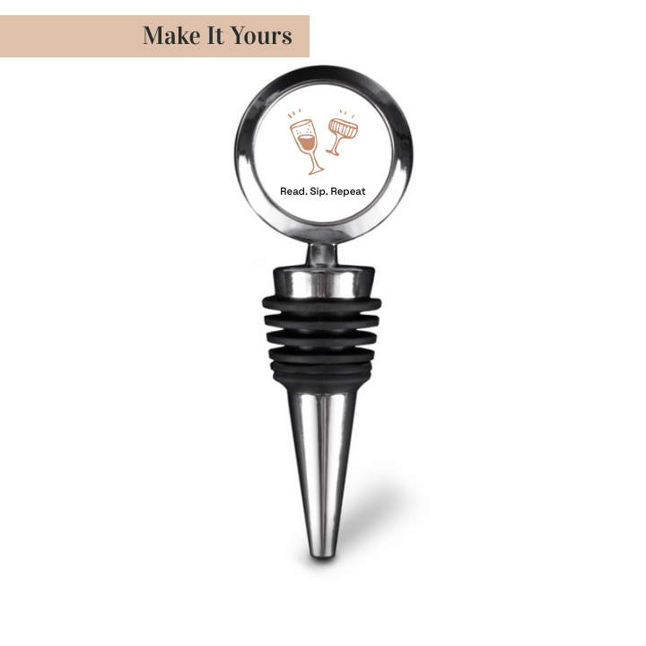 A stainless steel bottle stopper with a natural cork base and a round top featuring a book and wine glass design. The text 'Make It Yours' is visible on the image.