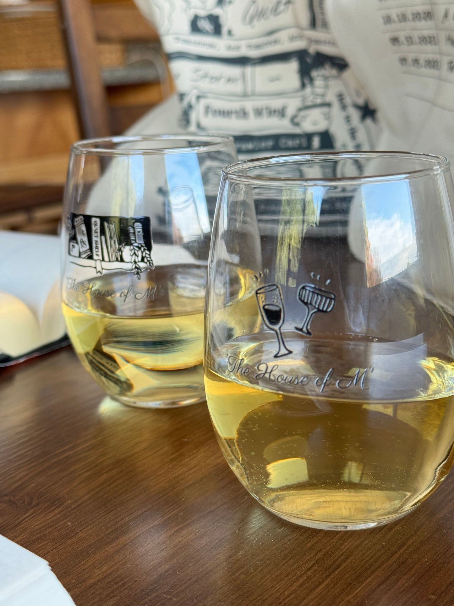 Two clear glass tumblers with black text and graphics on a wooden surface.