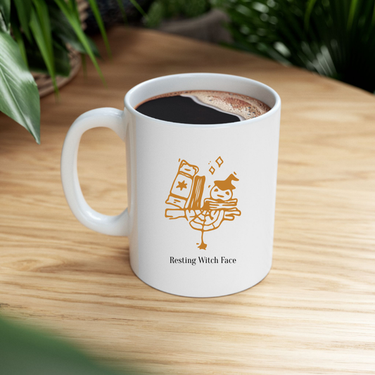 White mug with a witch face design and 'Resting Witch Face' text, filled with coffee on a wooden surface.