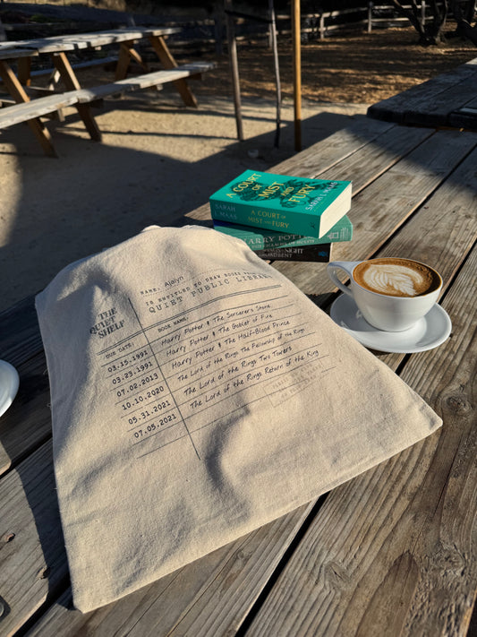 Open book with a cup of coffee and a tote bag on a wooden surface