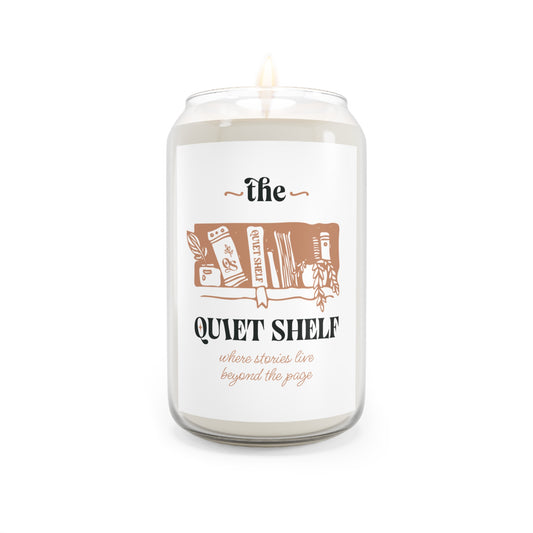 A soy candle in a clear glass jar with a minimalist label that features a book and the text 'the QUIET SHELF', with a lit wick, on a white background.